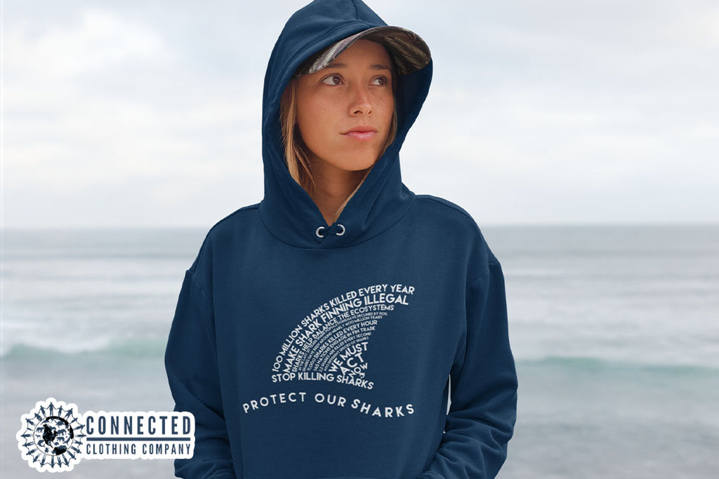 woman on the beach wearing navy blue Protect Our Sharks Unisex Hoodie - marktwainstoryteller - Ethically and Sustainably Made - 10% donated to Oceana shark conservation